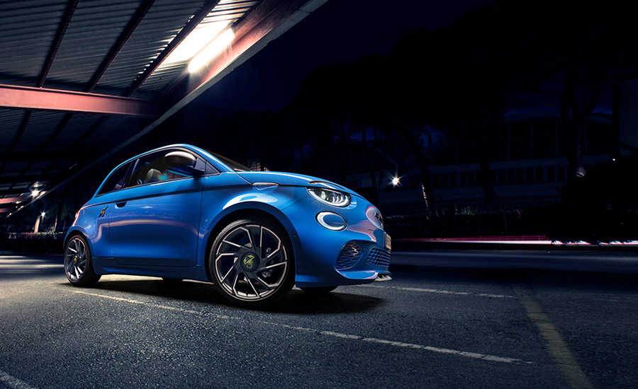A blue abarth electric hatch parked with dim lighting