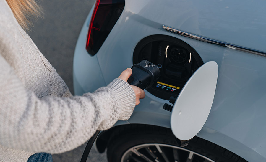 A blue electric car charger being plugged in