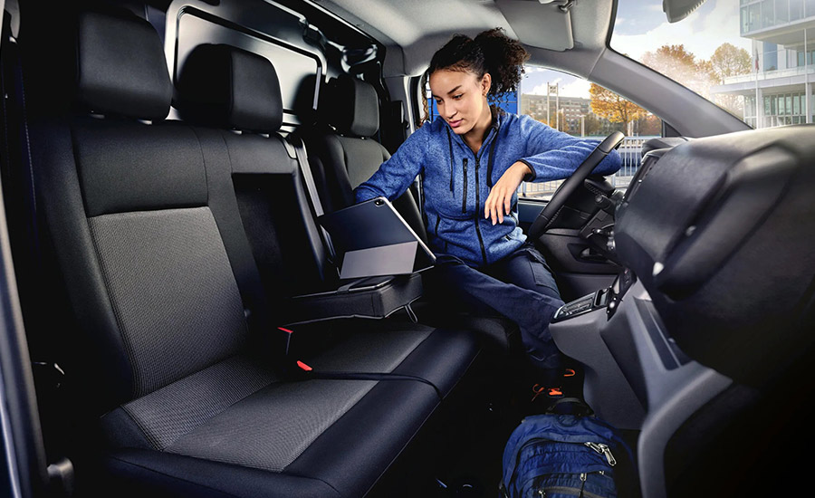 A woman sitting in the drivers seat using a laptop in a work van